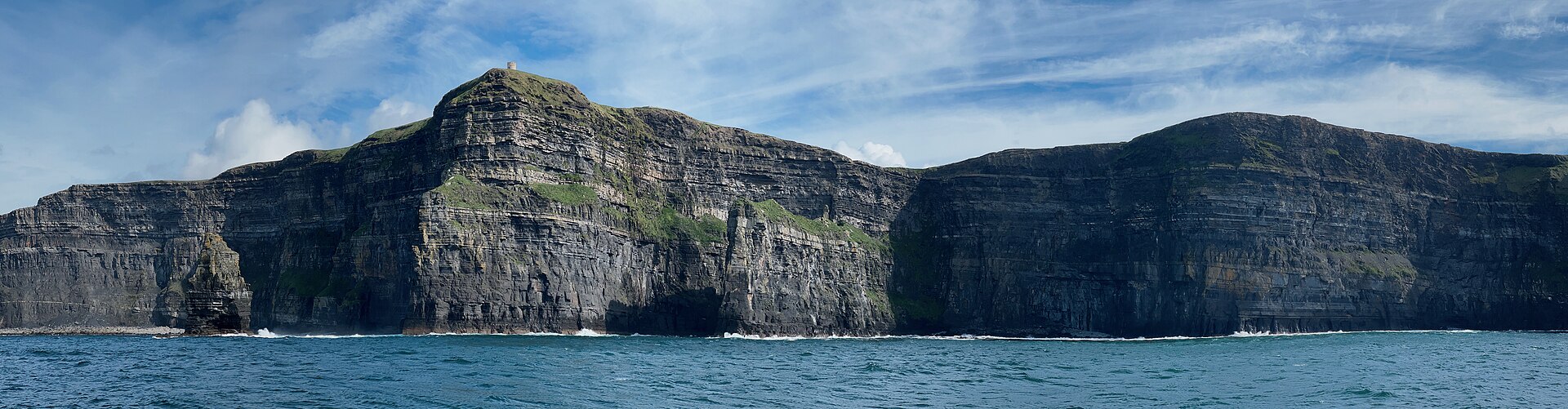 Vista panorâmica dos Cliffs of Moher a partir de um barco, com o mar em primeiro plano.